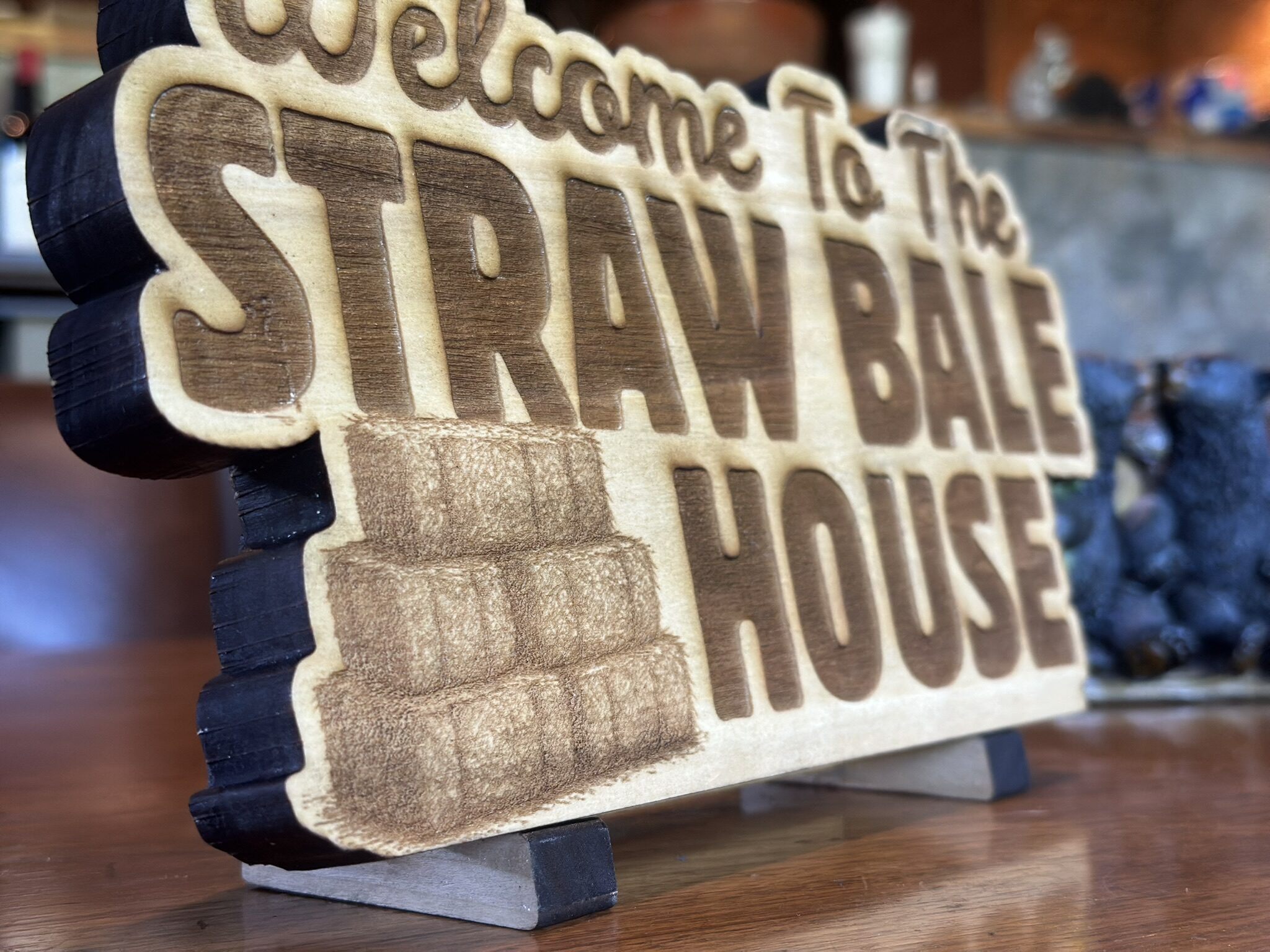 Low close view along an engraved wood sign, showing the depth of the cut letters.
