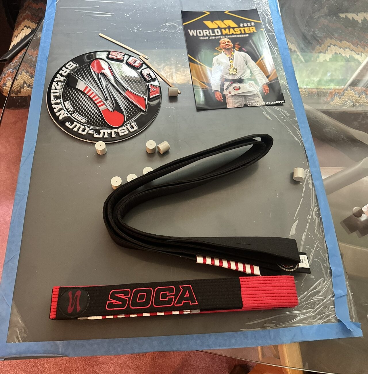 The contents laid out on the back panel: the round Soca logo, the photo, a folded belt and small standoffs.