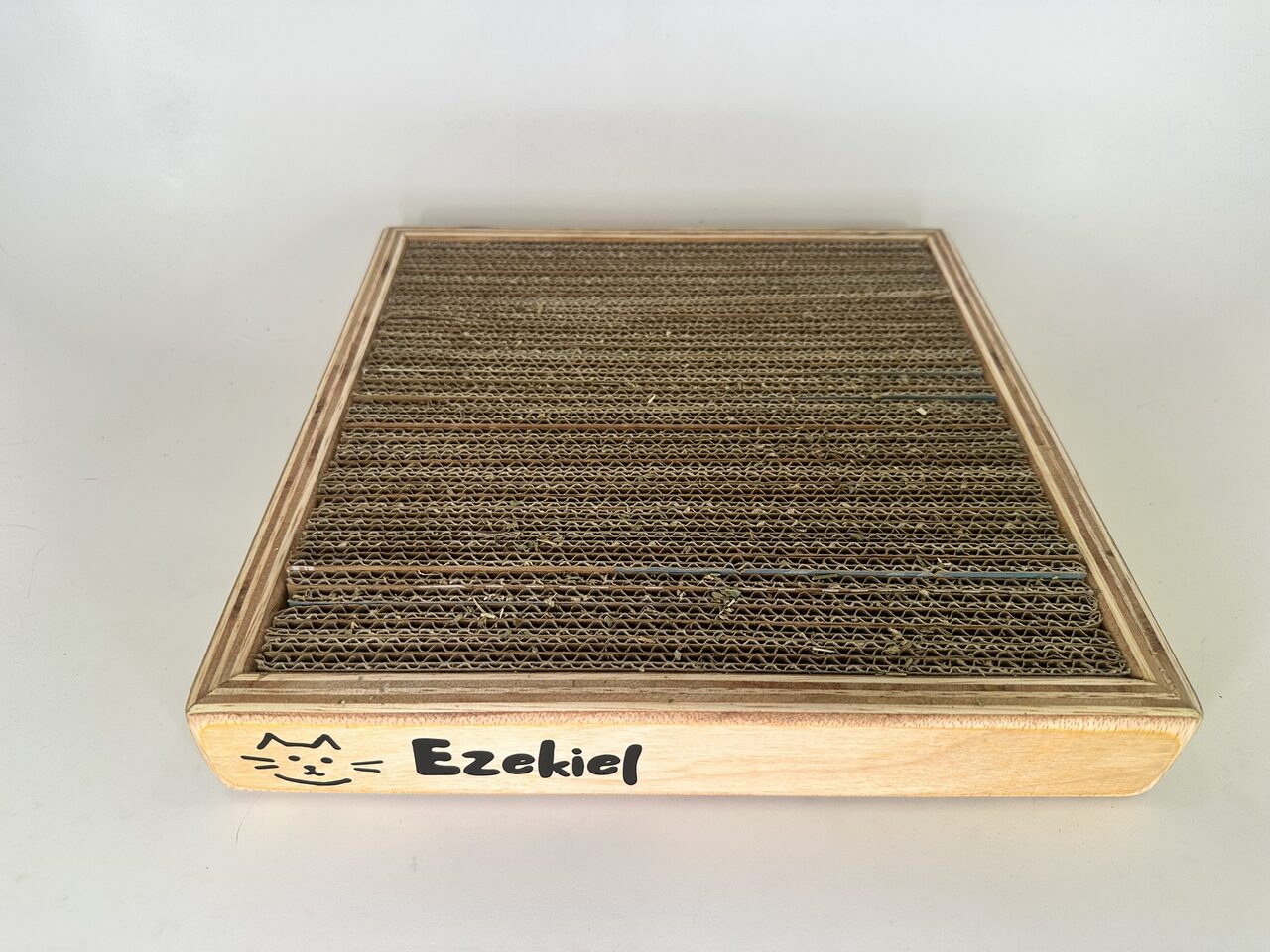 The scratcher box from a higher three-quarter angle on white, showing the full cardboard surface inside the plywood frame.