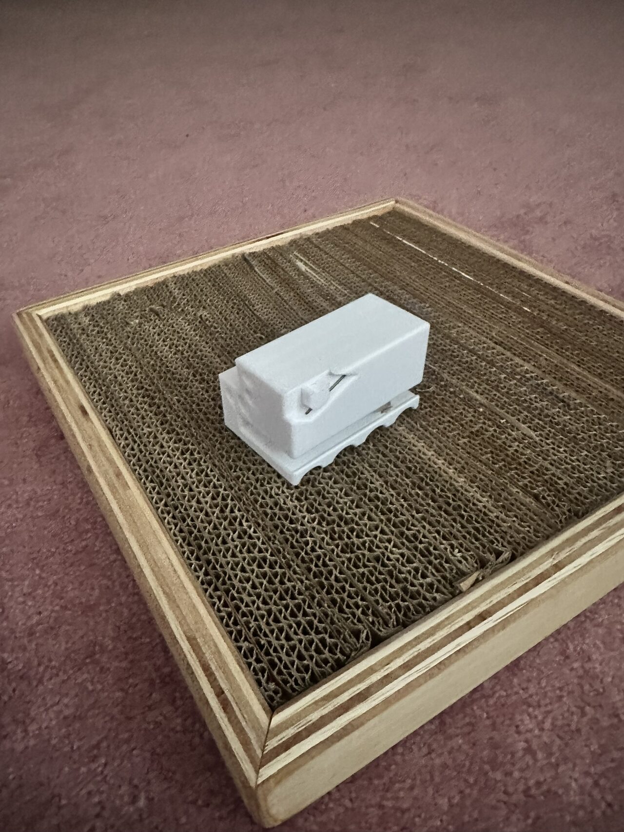 The white printed cutting guide sitting on top of the finished cardboard surface of the scratcher.