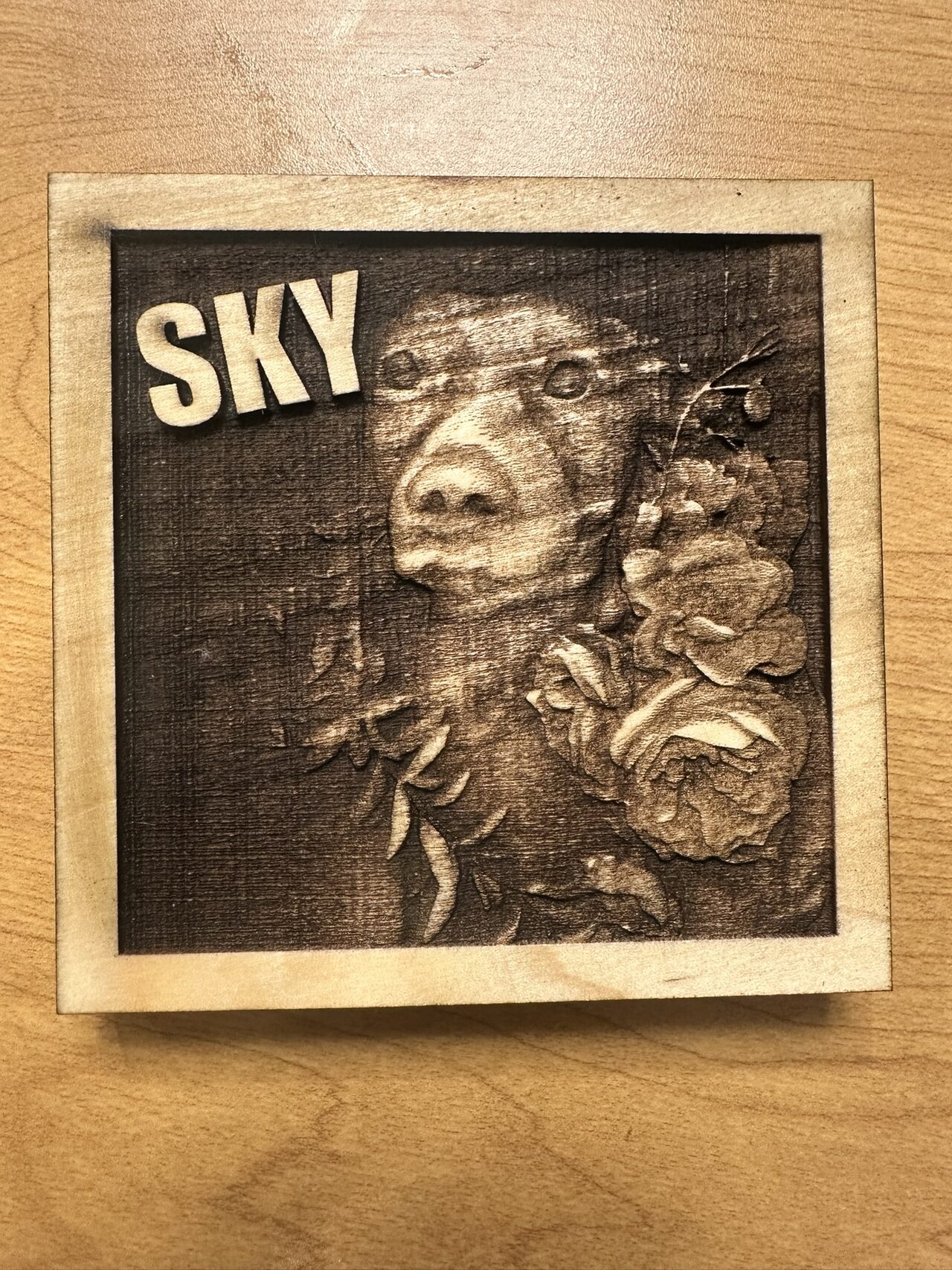Square wood plaque engraved with a dog beside roses, the name SKY in raised letters at top left.