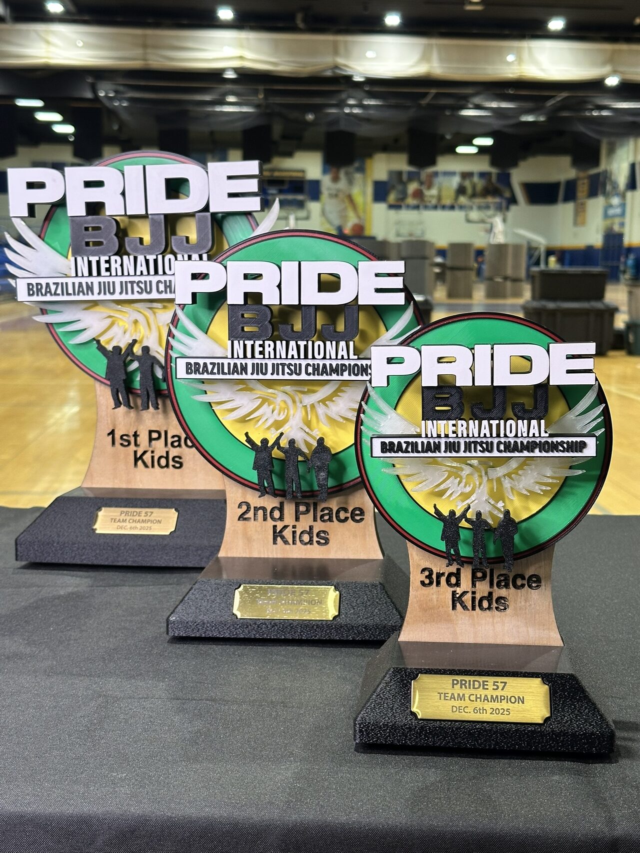 The 1st, 2nd and 3rd Place Kids trophies in a diagonal row on a black tablecloth.