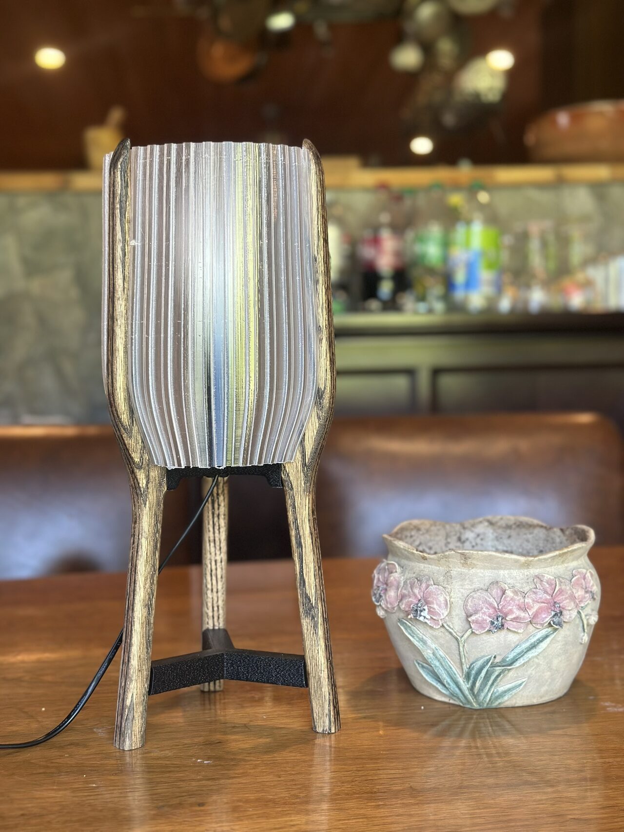 The lamp with its white shade switched off beside a ceramic bowl, the vertical ribs of the shade clearly visible