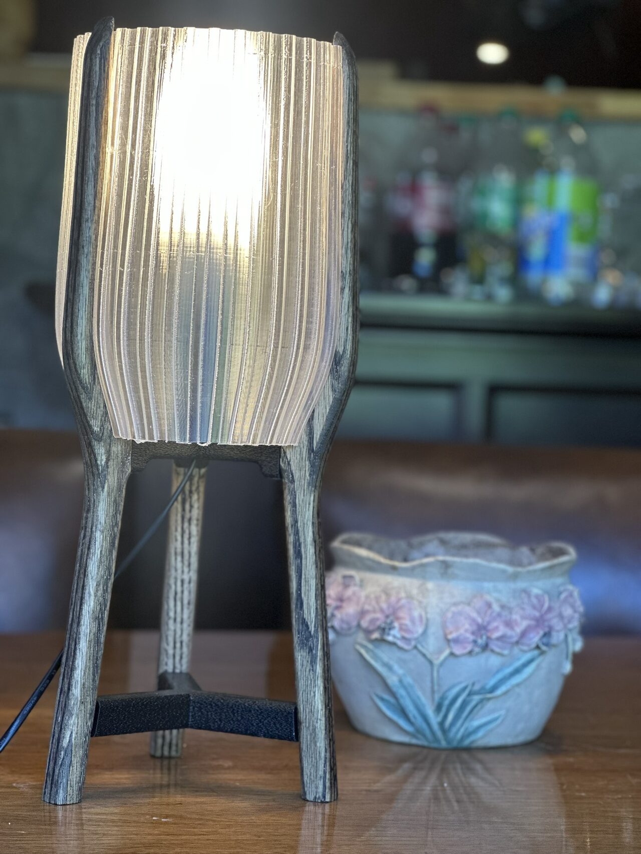 Close view of the lit white shade, the tops of the wooden legs and the black brace