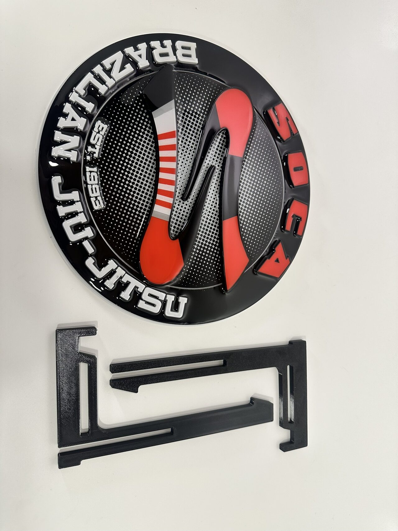 The medallion lying flat beside the two flat black pieces of its easel