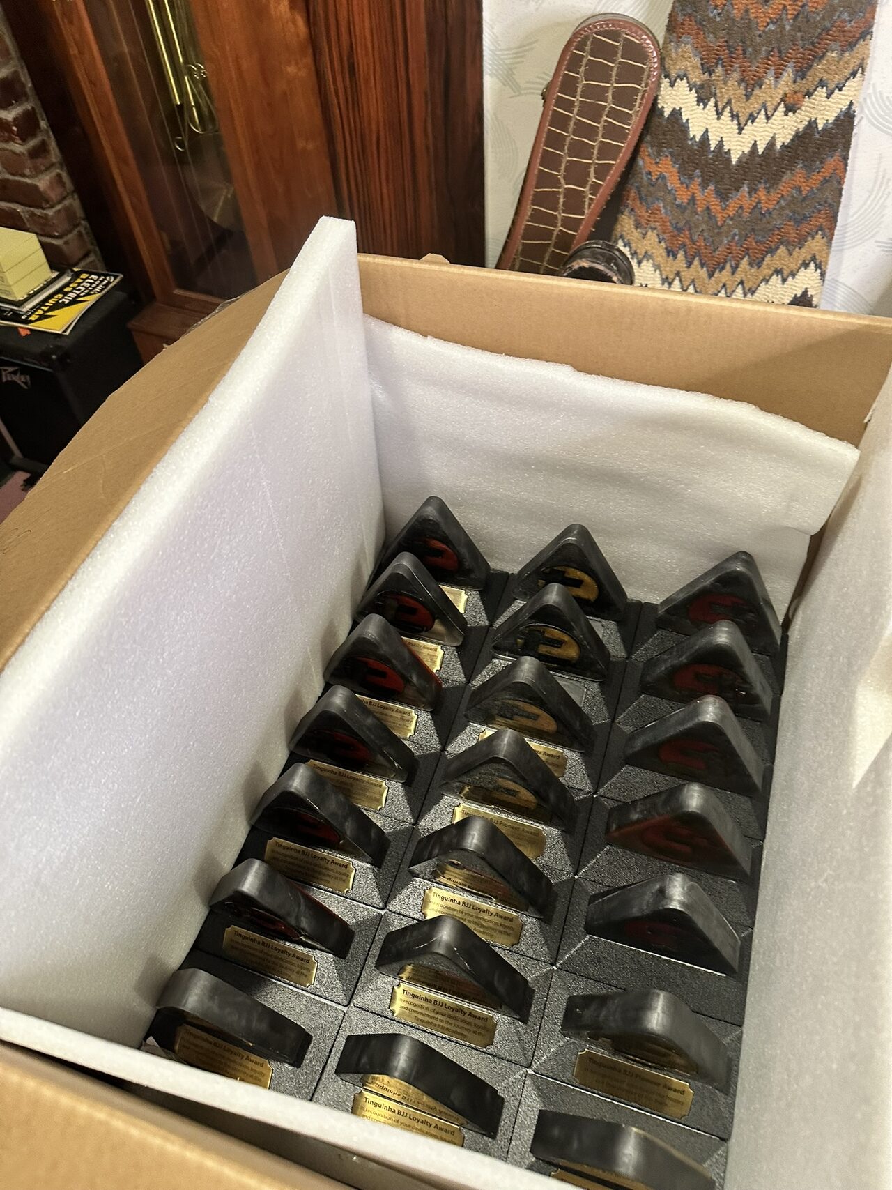Finished awards packed upright in rows inside a foam-lined cardboard box, seen from above.